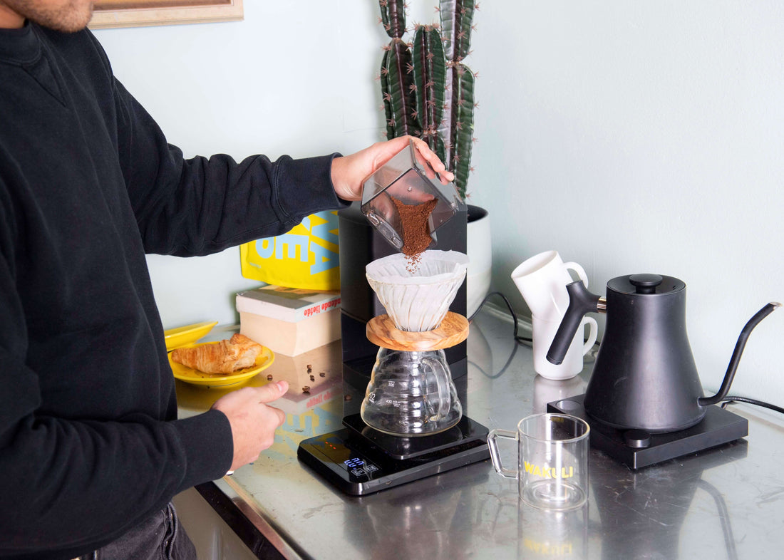 Hoeveel gram koffie per kopje - Jongen giet gemalen koffie in koffie filter als hij V60 koffie zet