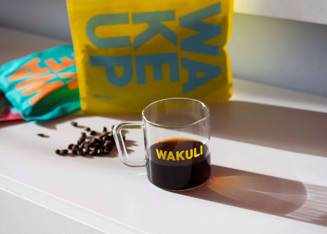 Licht gebrande koffiebonen - Wakuli pouches op tafel naast een kopje zwart koffie en koffiebonen