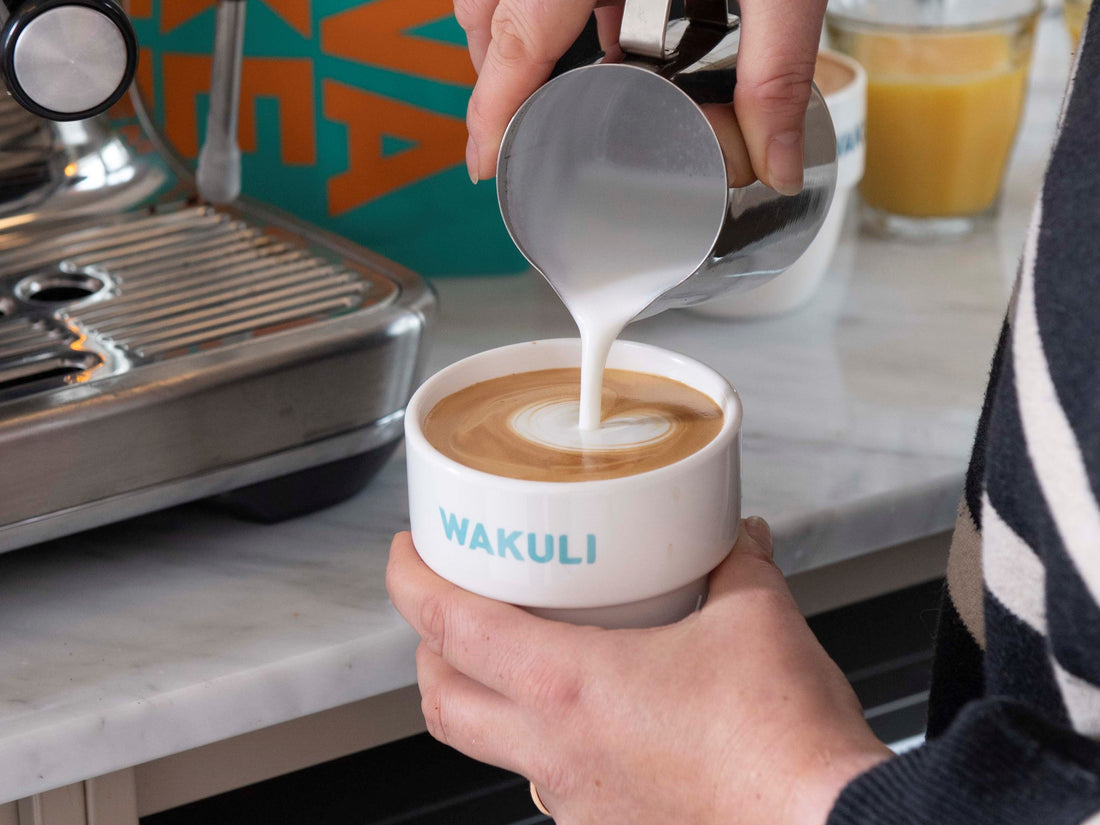 De beste cappuccino | Vrouw giet schuimende melk in Wakuli kopje