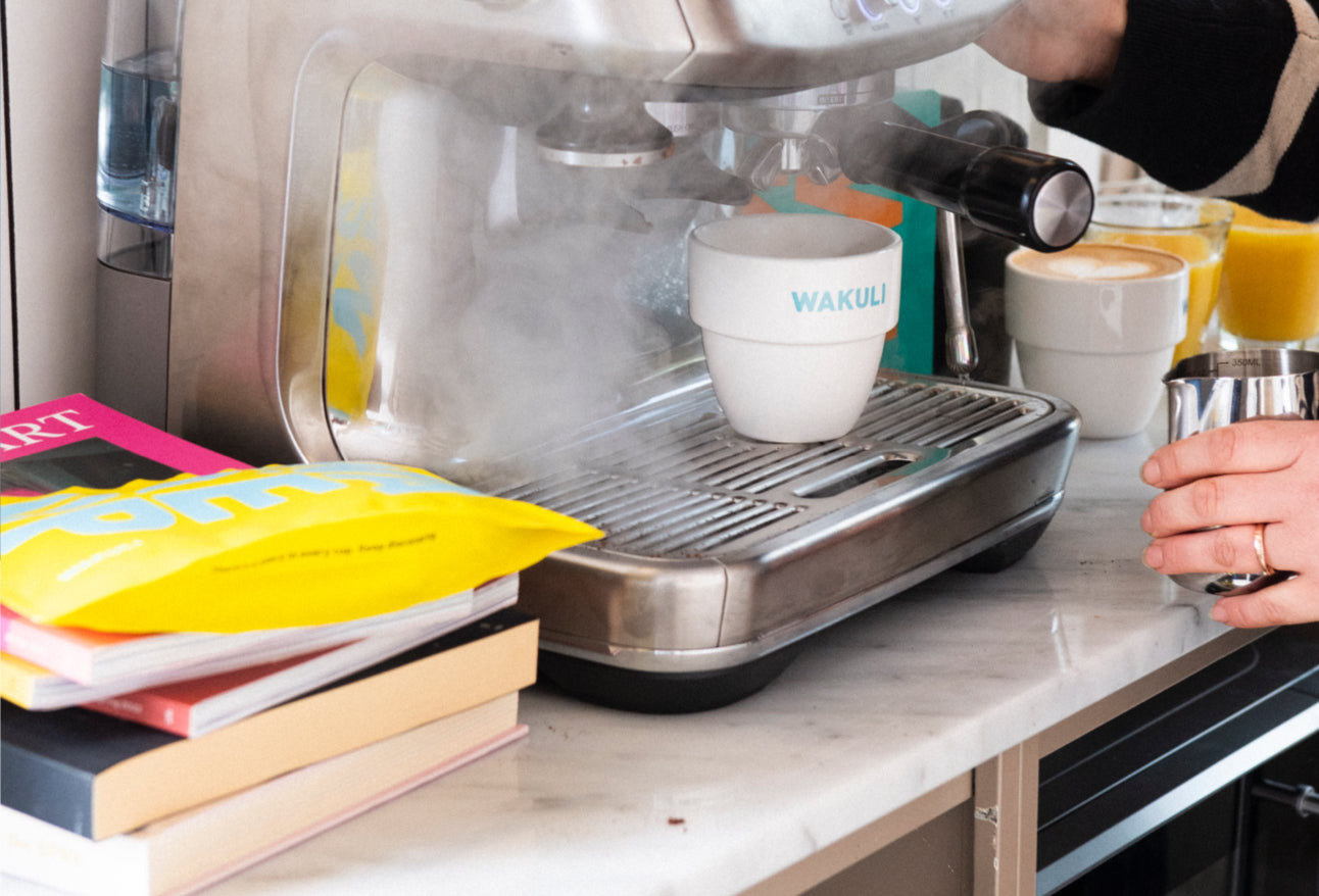 Verse koffiebonen - Stoom uit een espressomachine in een keuken. Wakuli koffiezakjes liggen ernaast. 