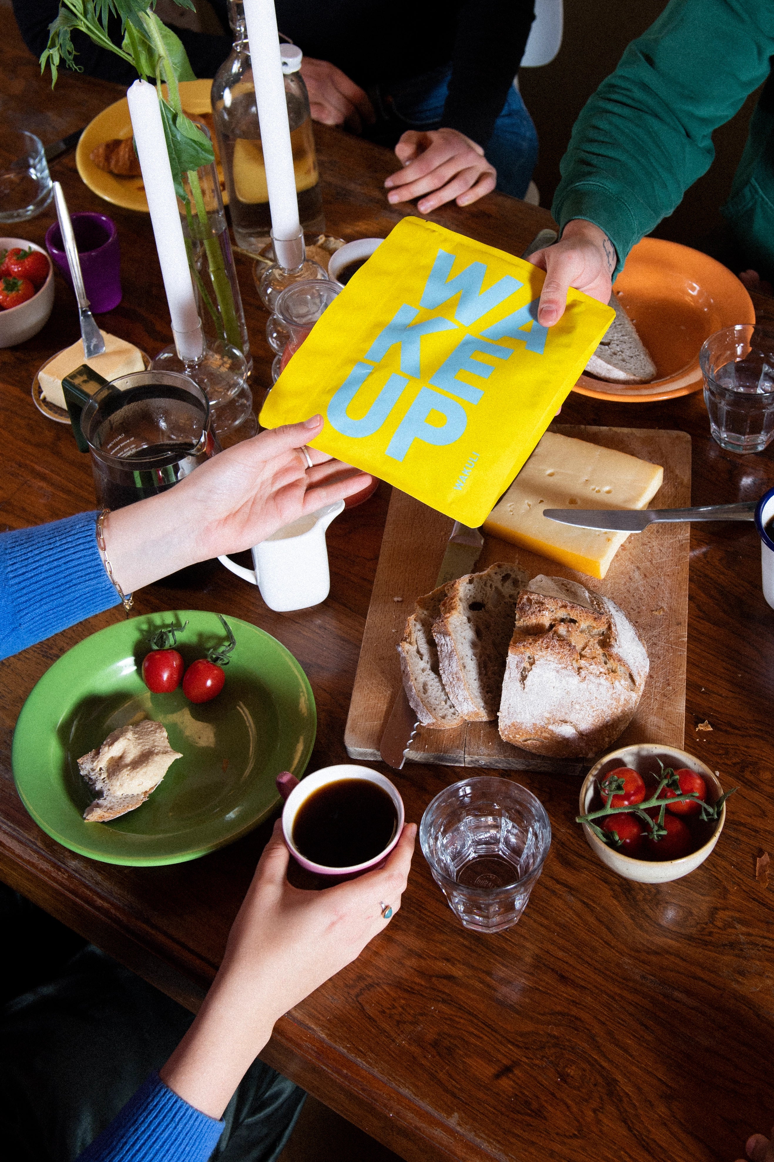 Coffee gifts - Iemand overhandigt een geel zakje aan een vriend aan de ontbijttafel